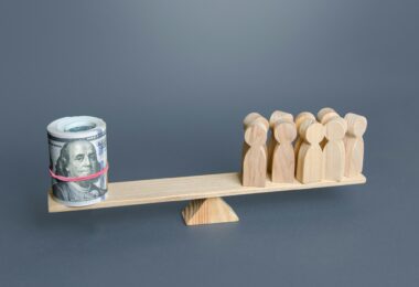 A group of people and money dollars on the scales.