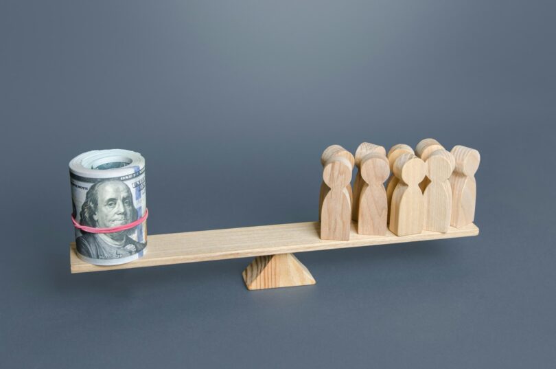 A group of people and money dollars on the scales.