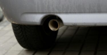 Closeup of a rear car exhaust pipe situated in a car's exhaust system