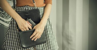 Photo of hand of young woman pulling a pistol out of her handbag with free copy space.