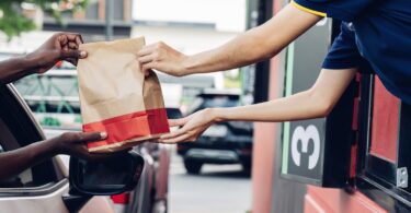 Hand Man in car receiving coffee in drive thru fast food restaurant.