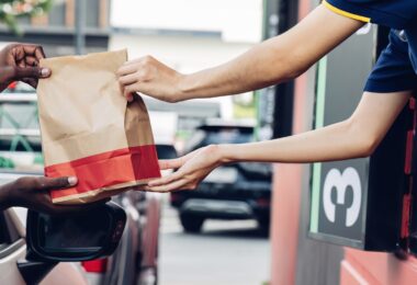 Hand Man in car receiving coffee in drive thru fast food restaurant.