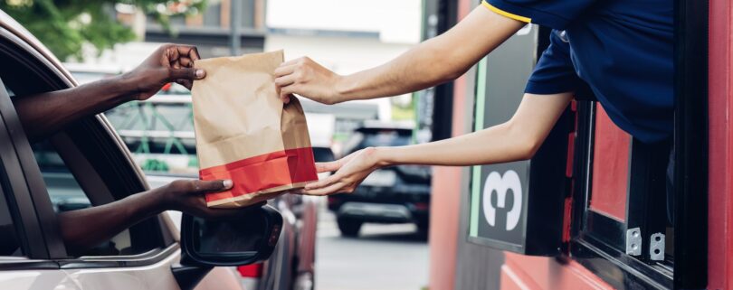 Hand Man in car receiving coffee in drive thru fast food restaurant.