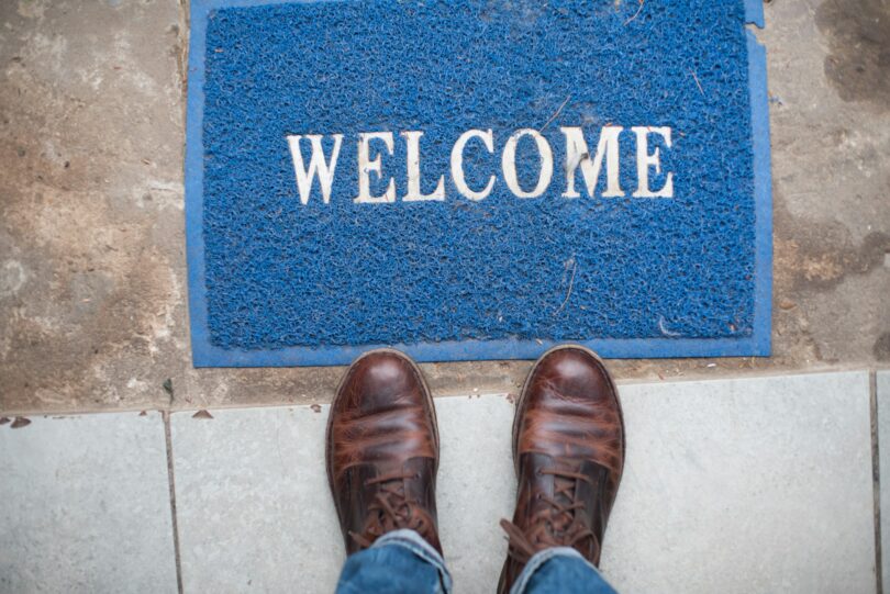 Welcome mat on ground with person standing next to it