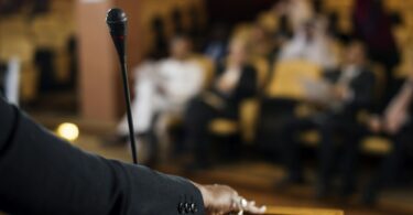 Hand of a Business Woman at a Podium with a Micrphpne