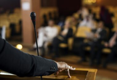 Hand of a Business Woman at a Podium with a Micrphpne