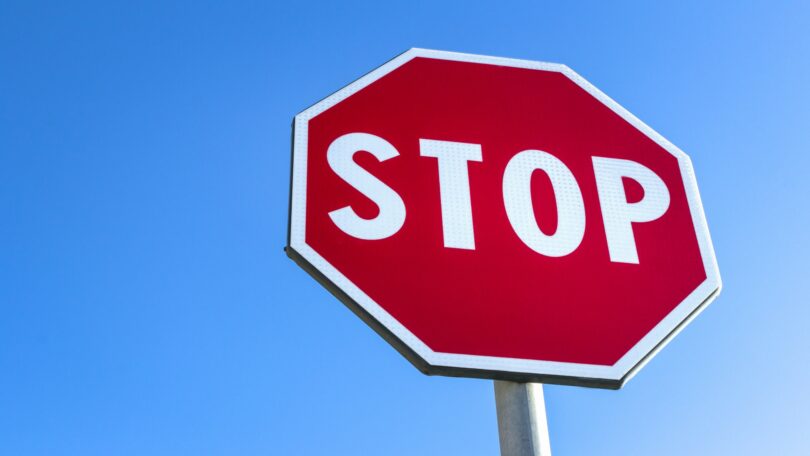 Red stop road sign and blue sky