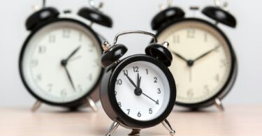 Different alarm clocks on table. Time change concept
