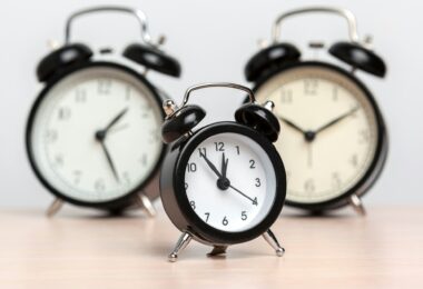 Different alarm clocks on table. Time change concept