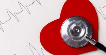Image of red heart and stethoscope on white surface with heart rate