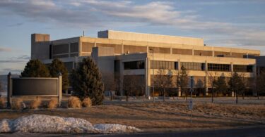 A modern data center with power lines and a substation on the Northern Colorado plains with mountains in the distance