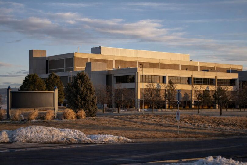 A modern data center with power lines and a substation on the Northern Colorado plains with mountains in the distance