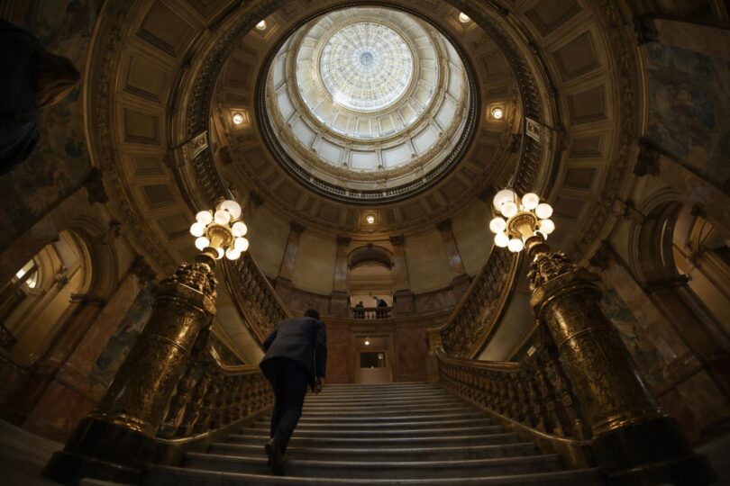 Budget papers and calculator on a desk with the Colorado State Capitol in the background
