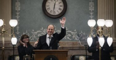 Lawmakers in a Colorado budget meeting with papers and the State Capitol nearby