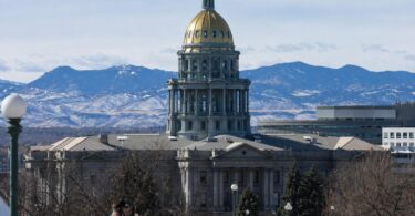 Officials and staff move through security at a Colorado government building or courthouse