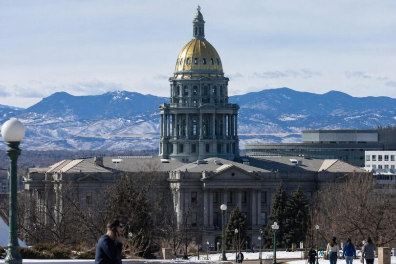 Officials and staff move through security at a Colorado government building or courthouse