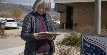Voter reviews a Colorado citizen initiatives petition on a clipboard near a county building