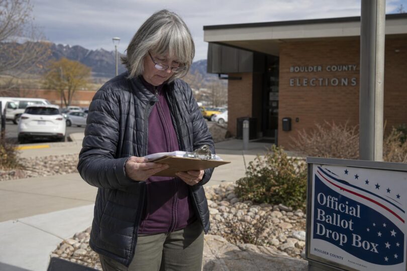 Voter reviews a Colorado citizen initiatives petition on a clipboard near a county building